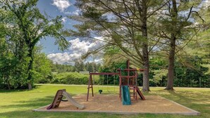 A playground with swings and a slide, surrounded by trees and grass. - Charming and casual motel in a great location with shared resort amenities (Lincoln)