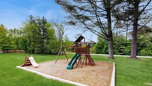 Un parque infantil con tobogán, estructura para escalar y columpios.