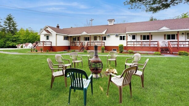 Un motel con una zona de estar al aire libre techada, un brasero y un césped bien cuidado.