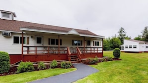 A single-story building with a porch, a staircase leading to the entrance, and a paved driveway. - Charming and causal motel in a great location with shared resort amenities (Lincoln)
