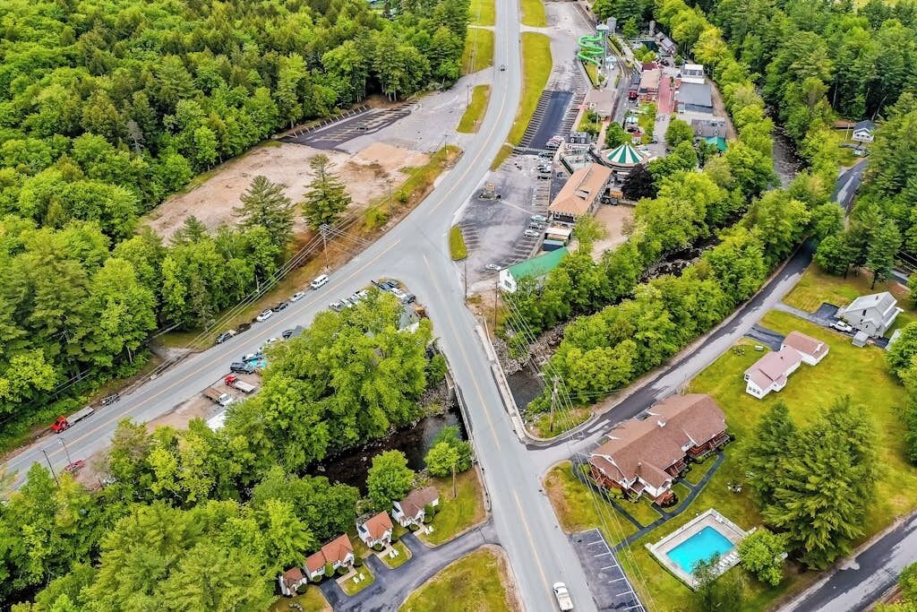 An aerial view of a residential area with multiple roads, houses, and a swimming pool.