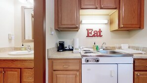 Una cucina con mobili in legno, un fornello, un lavello e un piano di lavoro con diversi oggetti.