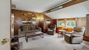 A cozy living room with a sofa, armchairs, a coffee table, and a fireplace.
