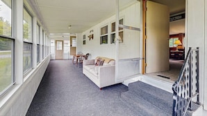 A corridor with a sofa, chairs, and a dining table.