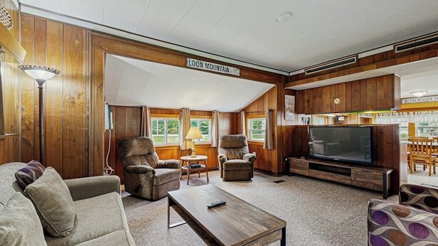 A cozy living room with a television, comfortable seating, and a sign reading 'LOON MOUNTAIN.'