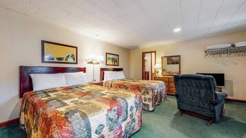 Een hotelkamer met twee bedden, een stoel, een televisie en kunstwerken aan de muren.