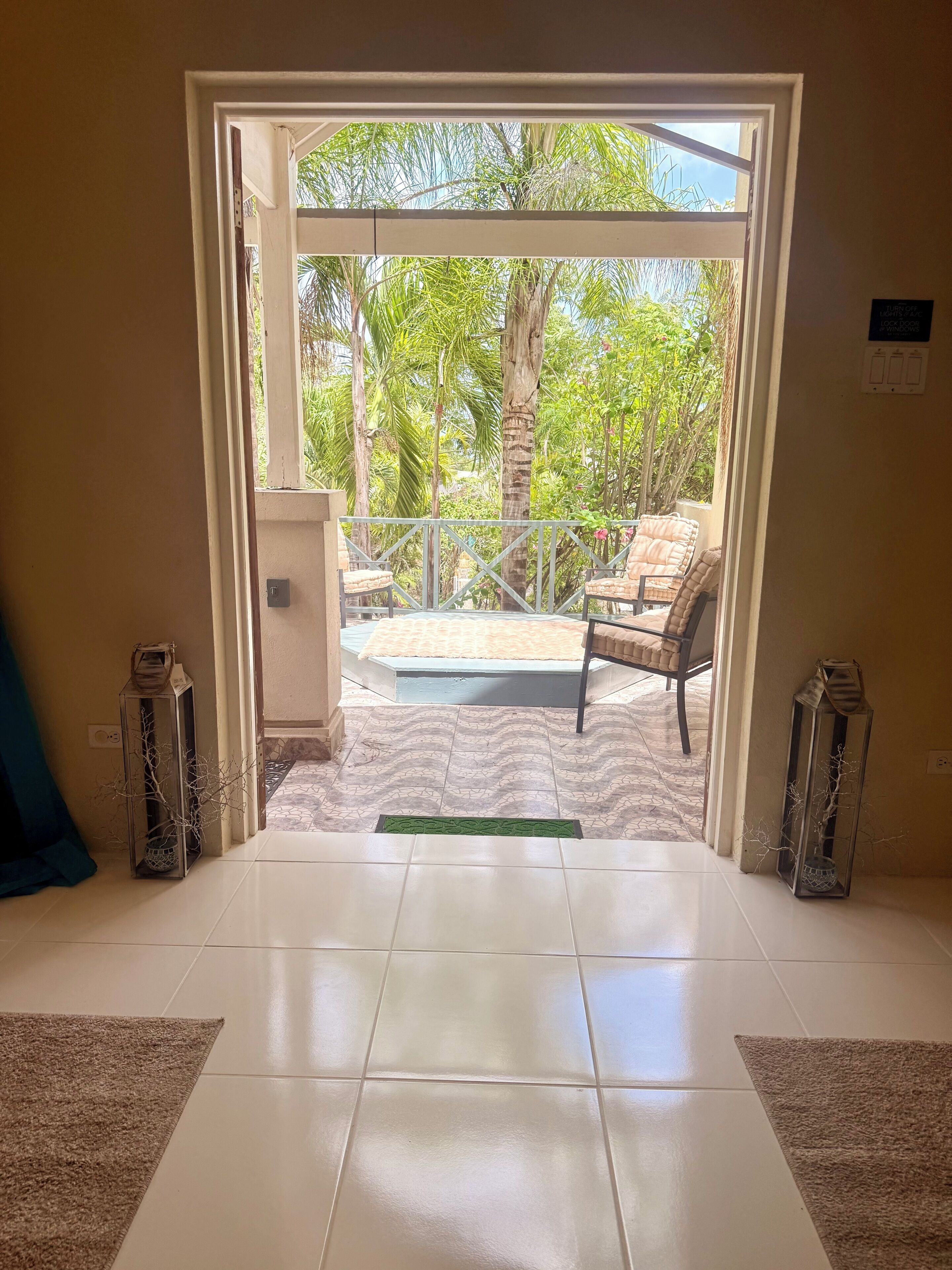 Une porte ouverte donne sur un patio équipé d’une piscine, de mobilier d’extérieur et offrant une vue sur la verdure.