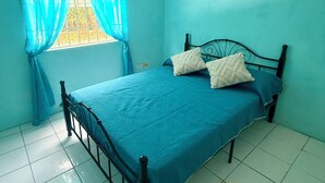 A room with a single bed, a window with curtains, and white tiled flooring. - Cozy 3-bedroom 2 and a half bathroom Townhome in beautiful Saint James with AC (Saint James)
