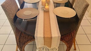 A dining table with a woven placemat, candles, and wicker chairs. - Cozy 3-bedroom 2 and a half bathroom Townhome in beautiful Saint James with AC (Saint James)