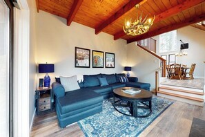 Ein Wohnzimmer mit einem Ecksofa, einem runden Couchtisch und einer Deckenleuchte.