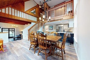 Ein Essbereich mit Holztisch und -stühlen, einer Treppe und einer Küche im Hintergrund.