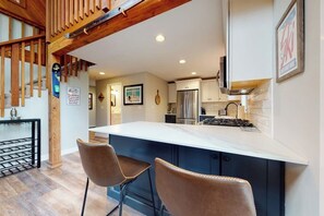 Eine moderne Küche mit einer großen Kochinsel, Barhocker und einer Holztreppe.