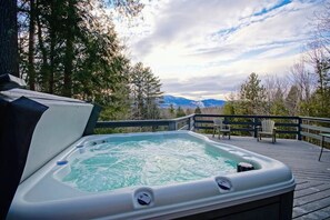 Ein Whirlpool auf einer Holzterrasse mit Blick auf die Berge.