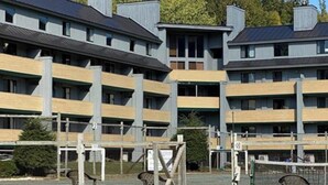 A multi-story building with a modern architectural design, featuring balconies and a covered outdoor area with seating.