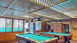A pool table with a green felt surface, wooden walls, and a ceiling with a lattice design.
