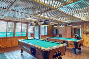 Ein Billardtisch mit grüner Spielbahn, Holzwänden und einer Decke mit Gittermuster.