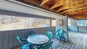 A covered porch with wooden beams, a round table, and four chairs.