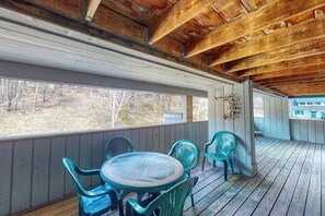 Eine überdachte Veranda mit Holzbalken, einem runden Tisch und vier Stühlen.