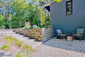A modern building with a stone retaining wall, outdoor seating, and a gravel pathway.