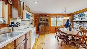 Una cucina con mobili in legno, un forno a microonde e un'area pranzo con tavolo e sedie.