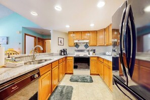 A modern kitchen with wooden cabinets, a stainless steel refrigerator, and a built-in oven. - Mountain-view, riverfront retreat with seasonal AC, pool, tennis, washer/dryer (Lincoln)