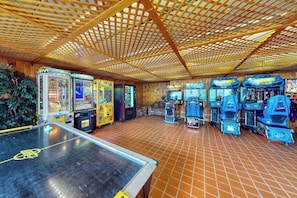 Ein Raum mit Spielautomaten, einem Tischtennis-Tisch und Holzvertäfelung.