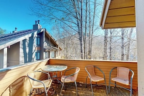 A wooden deck with four wicker chairs and a small round table, overlooking a forested area. - Mtn-view condo with 3 hot tubs, 4 pools, sauna, game room, tennis, fireplace (Lincoln)