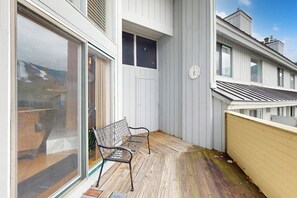 Ein Balkon mit einer Bank, einer Uhr und Blick auf das Meer.