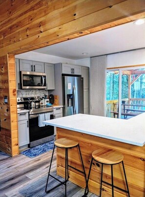 Una cocina moderna con armarios de madera, electrodomésticos de acero inoxidable y una isla grande con taburetes.