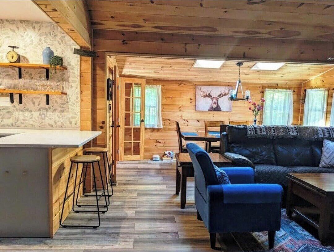 A wooden interior with a bar area, seating, and a dining table.