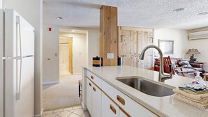 Una cucina moderna con mobili bianchi, un lavello in acciaio inossidabile e una parete d'accento in legno.