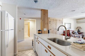 Eine moderne Küche mit weißen Schränken, einer Spüle aus Edelstahl und einer Wand mit Holzverkleidung.