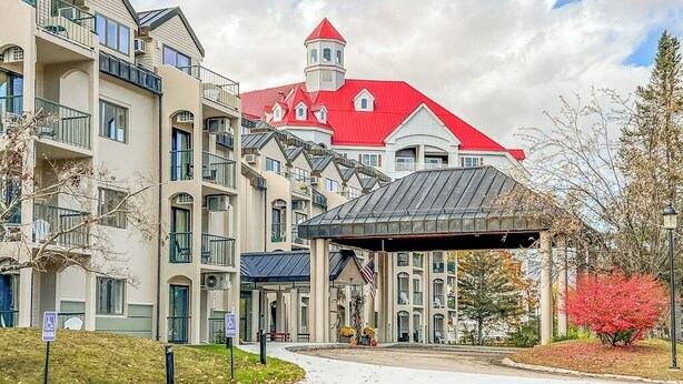Un hotel a più piani con un edificio a tetto rosso e un ingresso coperto.