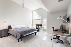 Ein Schlafzimmer mit Bett, Schreibtisch, Stuhl und einem großen Fenster.