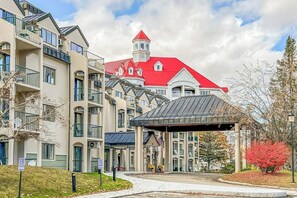 A multi-story hotel with a red-roofed building, balconies, and a covered entrance. - Mountainside condo w/ pool & rec room; walk to the ski lifts and downtown! (Lincoln)