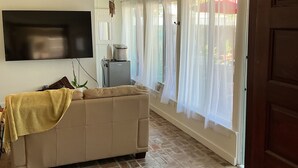 Een woonkamer met een bank, een flatscreen-tv, een koffiezetapparaat en een vloer met een baksteenmotief.