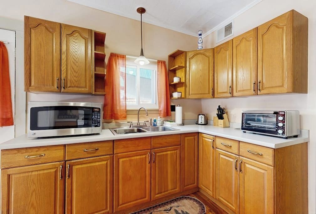 Una cucina con mobili in legno, un forno a microonde, un tostapane e un lavandino.