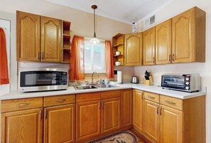 Una cocina con armarios de madera, microondas, tostadora y lavamanos.