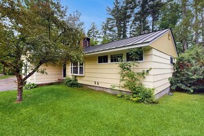 Ein eingeschossiges Haus mit Satteldach, einer Veranda und einem gepflegten Rasen.