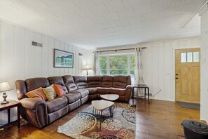 Ein Wohnzimmer mit einem braunen Ledersofa, einem kleinen Tisch und einem gemusterten Teppich.
