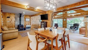 Un interior de madera con una mesa de comedor, sillas, un sofá, una chimenea y un televisor.