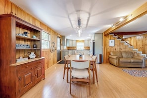 Ein Holzkamin mit einem Esstisch, Stühlen, einer Couch und einer Treppe.