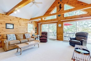 A spacious living area with a wooden ceiling, large windows, a sofa, a recliner, and a coffee table. - Stunning lakefront home with private dock, deck, firepit, and lake view (Wakefield)