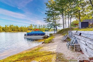 Une jetée au bord du lac, avec un bateau, un banc en bois et un abri.