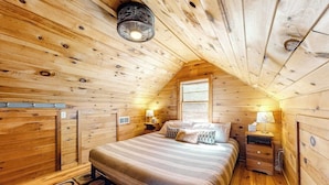A cozy wooden cabin bedroom with a bed, nightstands, and a window.