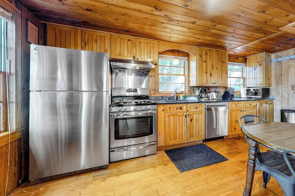 Eine Küchenzeile im Holzblockhausstil mit einem Edelstahlkühlschrank, Backofen und einer Mikrowelle.
