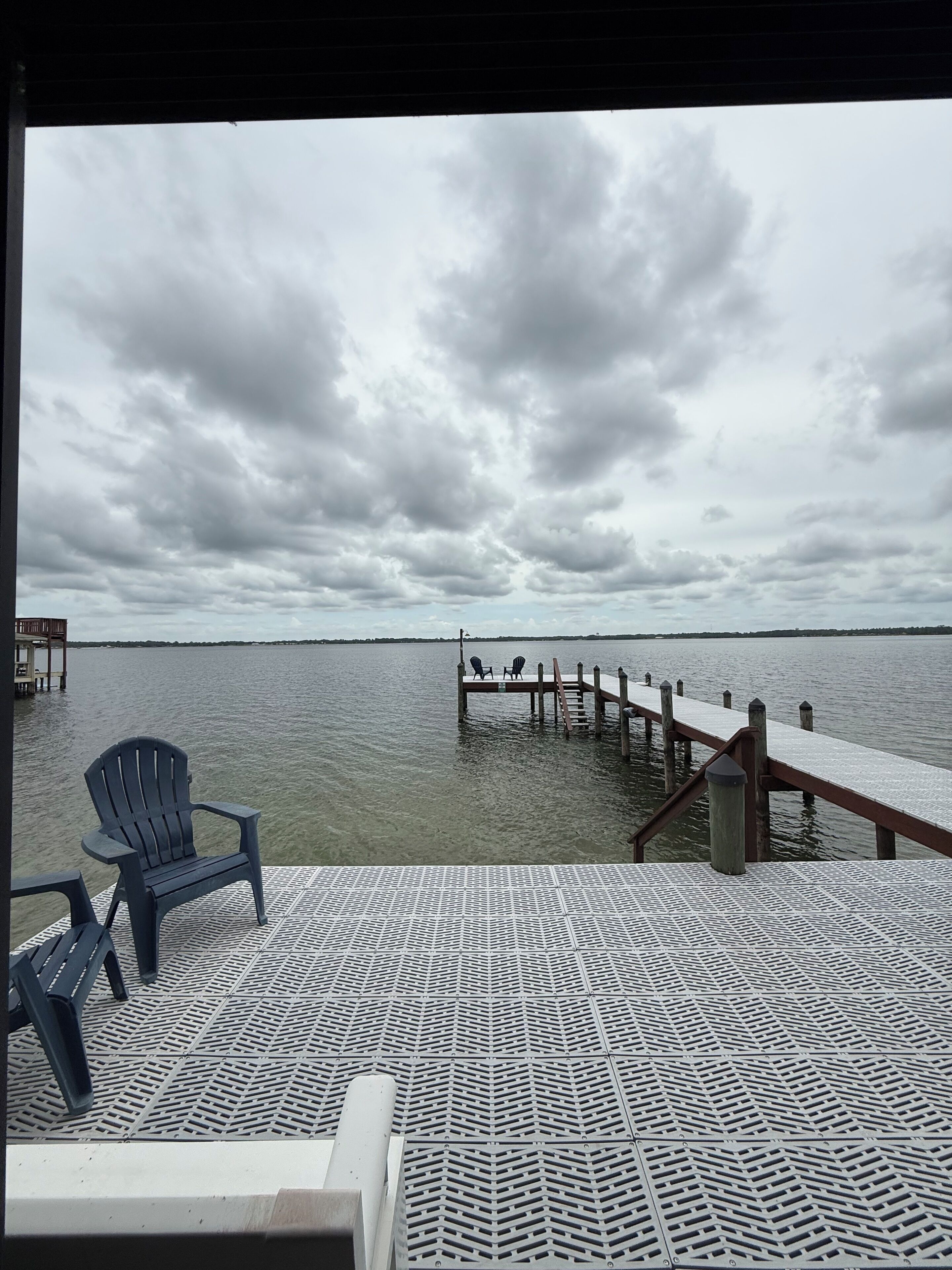 A pier extending into a body of water with a cloudy sky above.