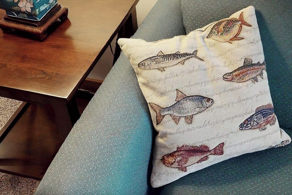 Un canapé agrémenté d’un coussin orné d’illustrations de poissons.