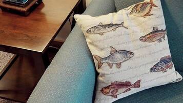 Un canapé agrémenté d’un coussin orné d’illustrations de poissons.