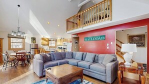 A spacious living area with a sectional sofa, a wooden coffee table, and a red accent wall. - Open concept home close to the beach with gas fireplace and deck (Madison)
